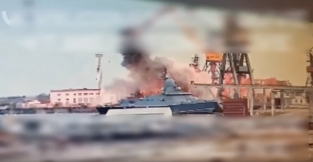 A burning ship in a harbor.