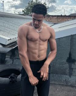 Shirtless man with muscular physique wearing black pants.