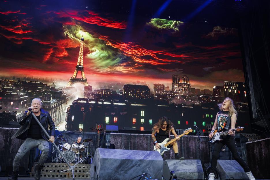 Iron Maiden performs on stage with a backdrop of the Eiffel Tower and Notre Dame.