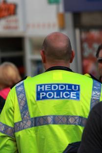 Back of a Welsh police officer's bright yellow jacket.