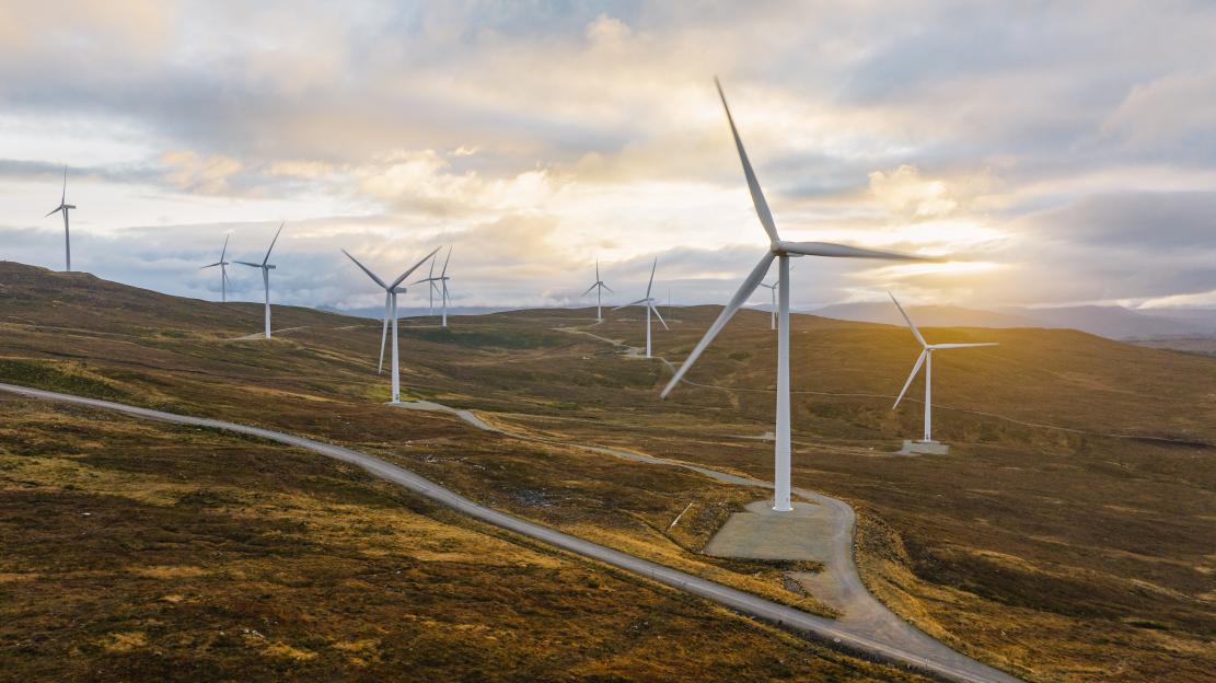 Aerial view of a wind farm on a Scottish hillside at sunset.