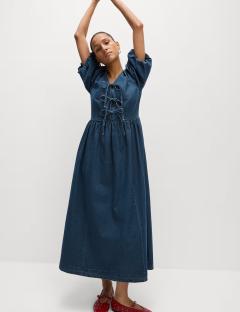Model wearing a denim midi dress with tie detailing.