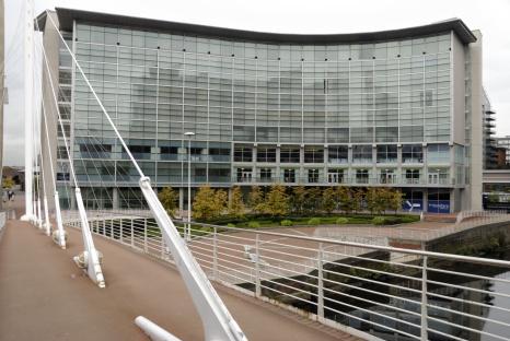 Hotel with glass facade and bridge.