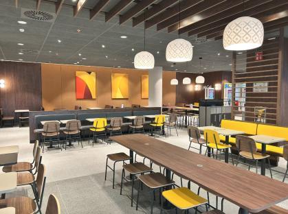 Interior of a large McDonald's restaurant with yellow chairs and wooden tables.