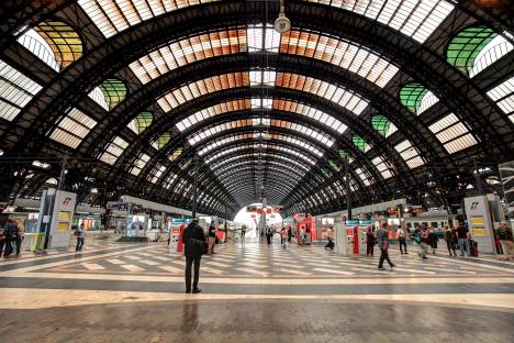 Milano Centrale train station interior with passengers and trains.