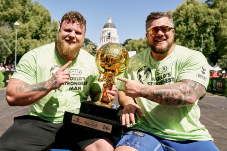 Two strongmen holding the World's Strongest Man trophy.