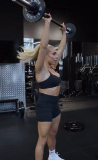 Woman performing overhead barbell press.