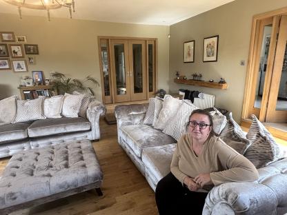 Woman sitting on a silver sofa in her living room.