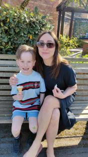 Woman and young boy sitting on a bench, the boy eating an ice cream cone.