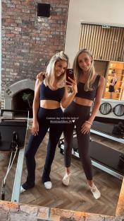 Two women in workout clothes taking a selfie in a Pilates studio.