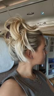 Woman with blonde hair in a bun on an airplane.