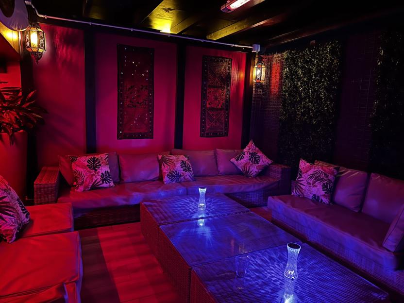 Lounge area with wicker furniture and colorful lighting.