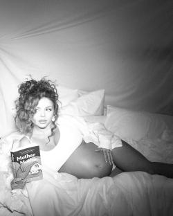 Black and white photo of a pregnant Jesy Nelson in bed reading