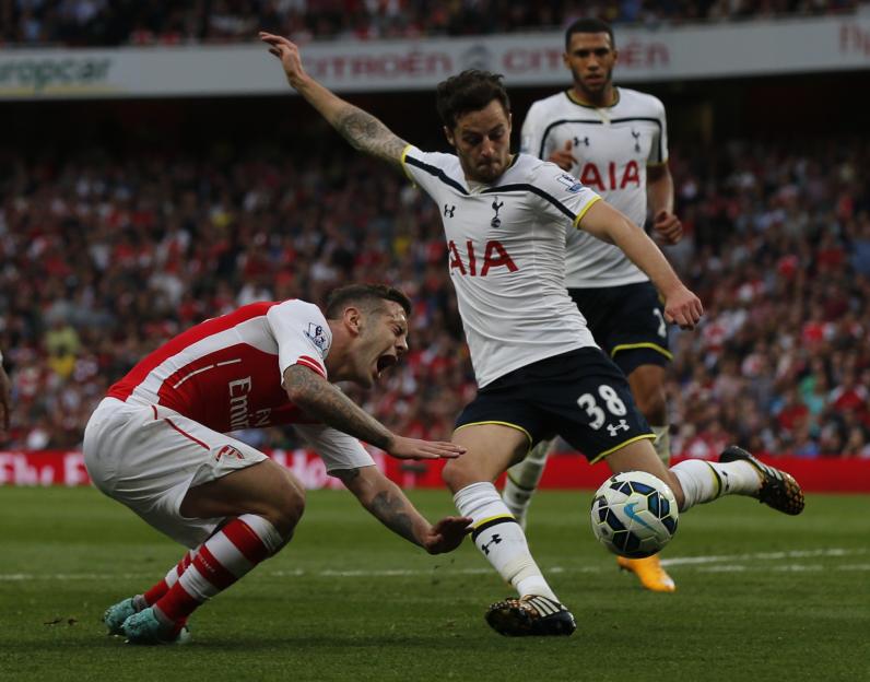 Arsenal's Jack Wilshere and Tottenham Hotspur's Ryan Mason fight for the ball during a soccer match.