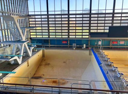 Empty indoor swimming pool with diving boards.