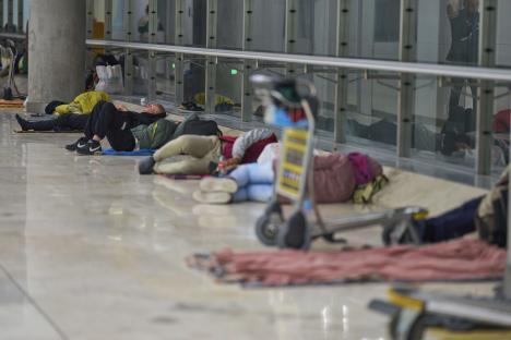 People sleeping on the floor of an airport terminal.