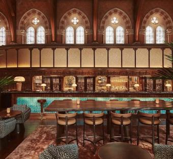 Long bar and seating area in a room with arched windows.