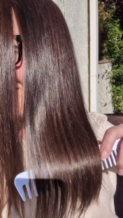 Person combing long brown hair.