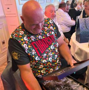 Man opening a gift at a formal event.