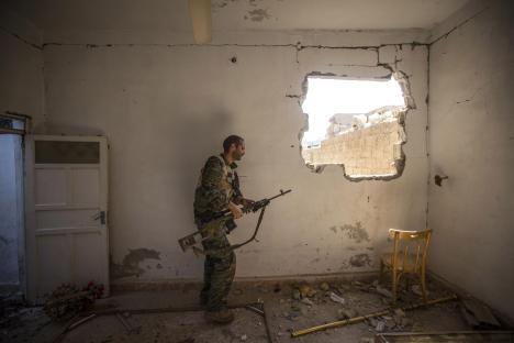 A British volunteer fighter with the Syriac Military Council holds a rifle in a damaged building in Raqqa, Syria.