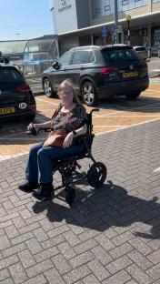Woman in wheelchair in parking lot.