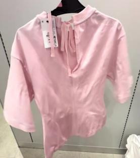 Pink cinch waist T-shirt on a hanger.