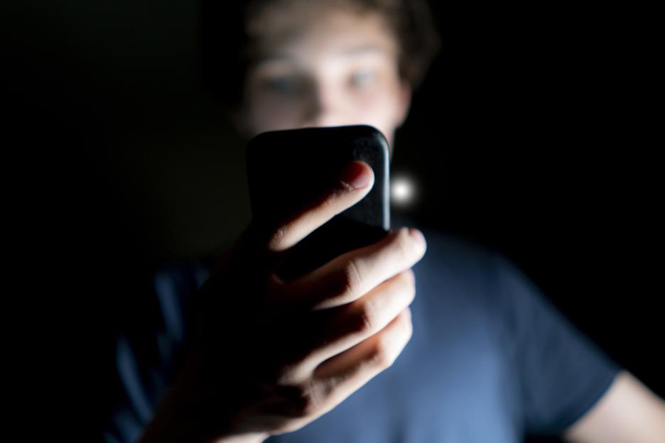 Young man using a mobile phone in a dark room.