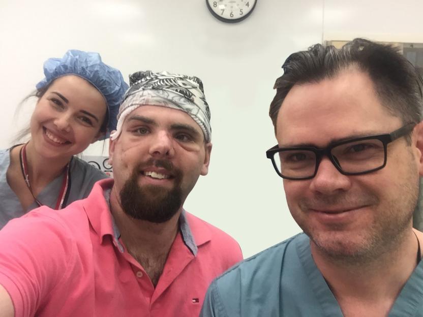Selfie of a man with facial injuries, a female nurse, and a male doctor.