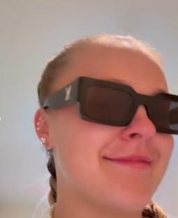 Close-up of a person wearing sunglasses and a pearl necklace.