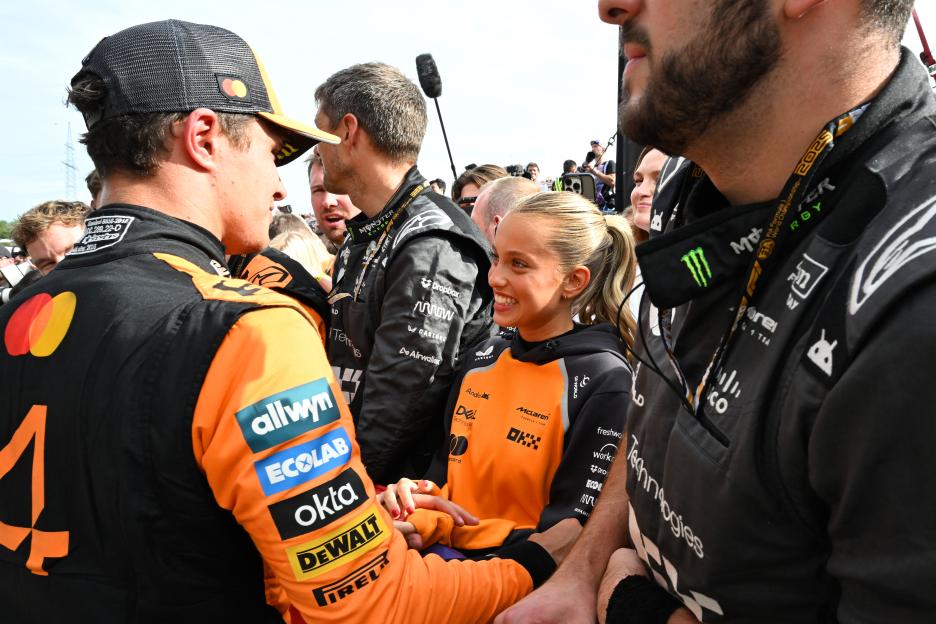 A group of people in orange racing suits celebrating.