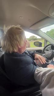 Boris Johnson being bitten by an ostrich in a car.