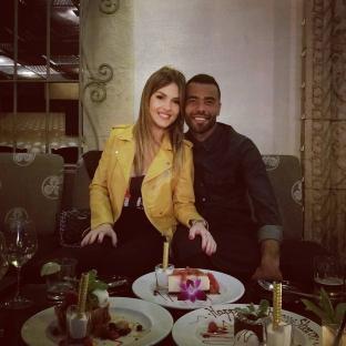 Ashley Cole and Sharon Canu at a restaurant, celebrating with dessert.