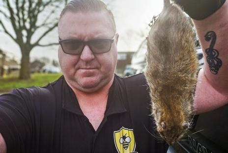 Pest controller holding a large rat.