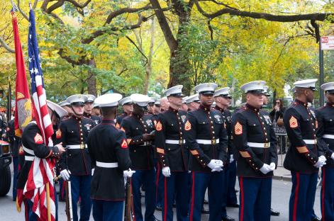 Marine Corps soldiers in uniform at a Veterans Day parade.