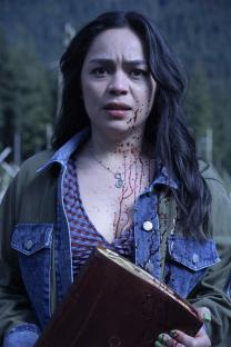 A bloody woman holds a book in Final Destination: Bloodlines.