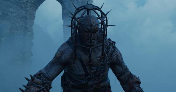 Ogre-like creature in chains and spiked cage.