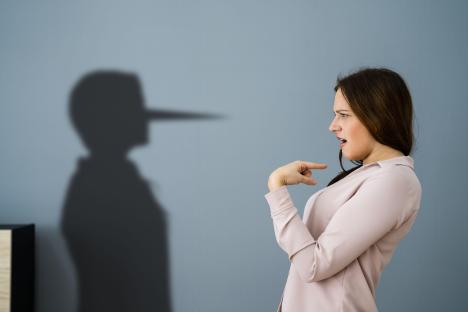 Woman pointing at her shadow with a Pinocchio-like nose.