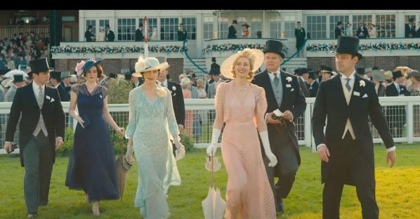 Group of people in 1920s attire walking on a lawn.