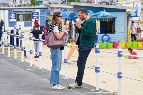 Couple eating ice cream on a seaside promenade.