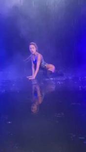 Woman in a bodysuit twerking in the rain.
