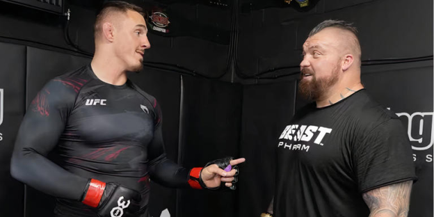 Two men talking, one in a UFC shirt and the other in a Beast Pharm shirt.