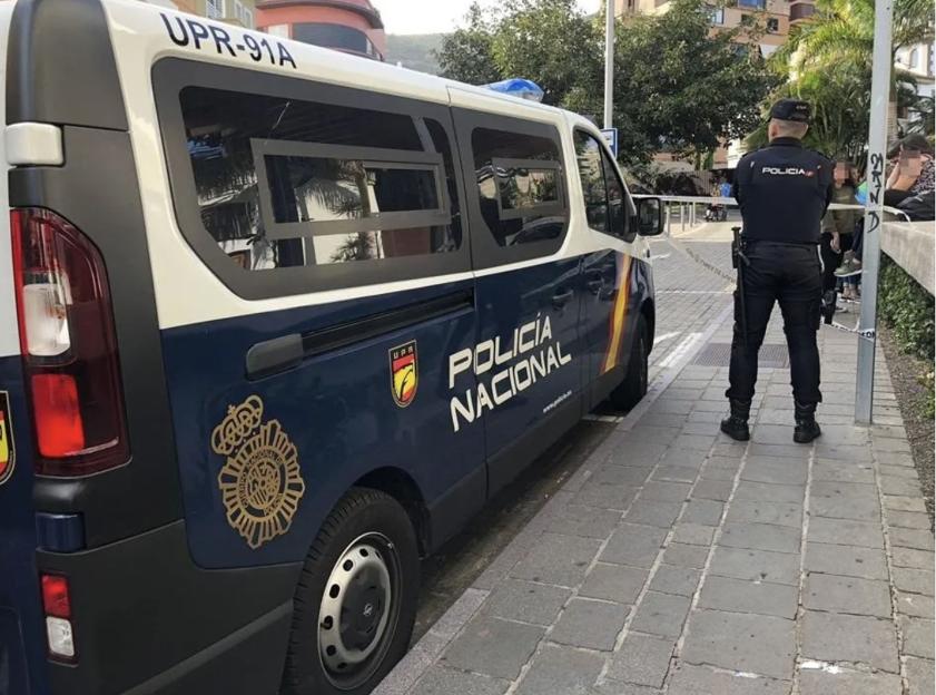 A Spanish National Police officer standing next to a police van.