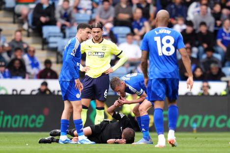 Soccer referee injured on the field, attended to by players.