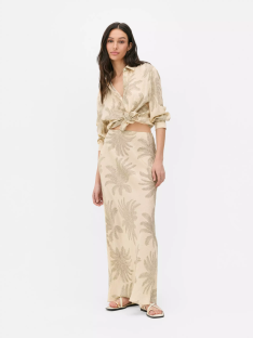 Woman in beige palm-print shirt and maxi skirt.
