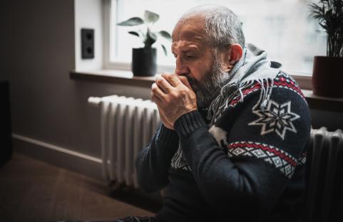 Man warming hands near radiator.