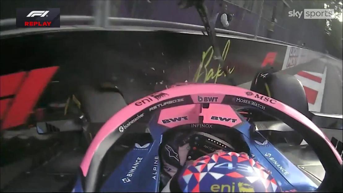Onboard view of a Formula 1 car during the Azerbaijan Grand Prix, showing the driver's helmet and pink steering wheel.