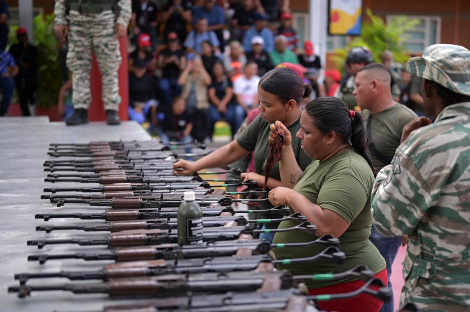 Two women, participating in a Bolivarian National Armed Forces drill, train with weapons alongside other citizens in Caracas, Venezuela.