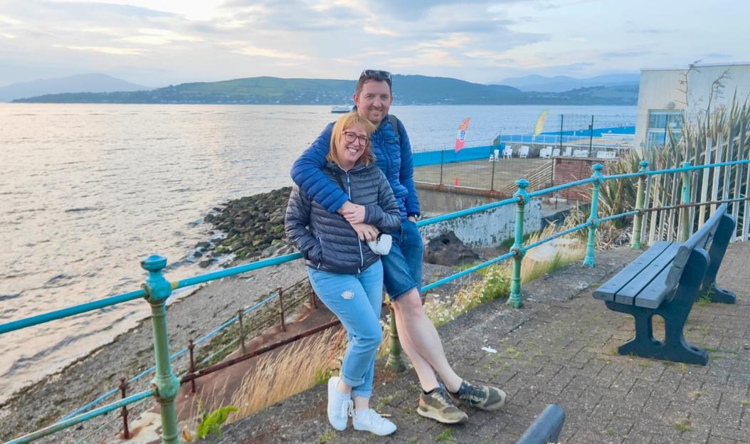 Couple posing near a sea railing.