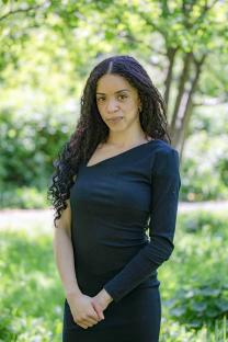 Portrait of a woman with long curly hair wearing a black dress.