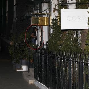 A person standing outside Core by Clare Smyth restaurant at night.